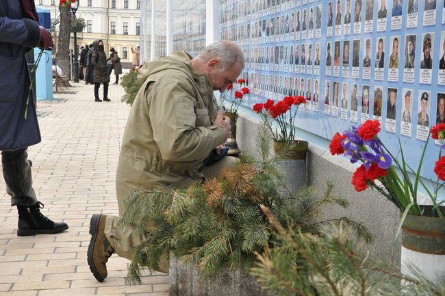 Чоловік молиться біля Стіни пам'яті полеглих за Україну